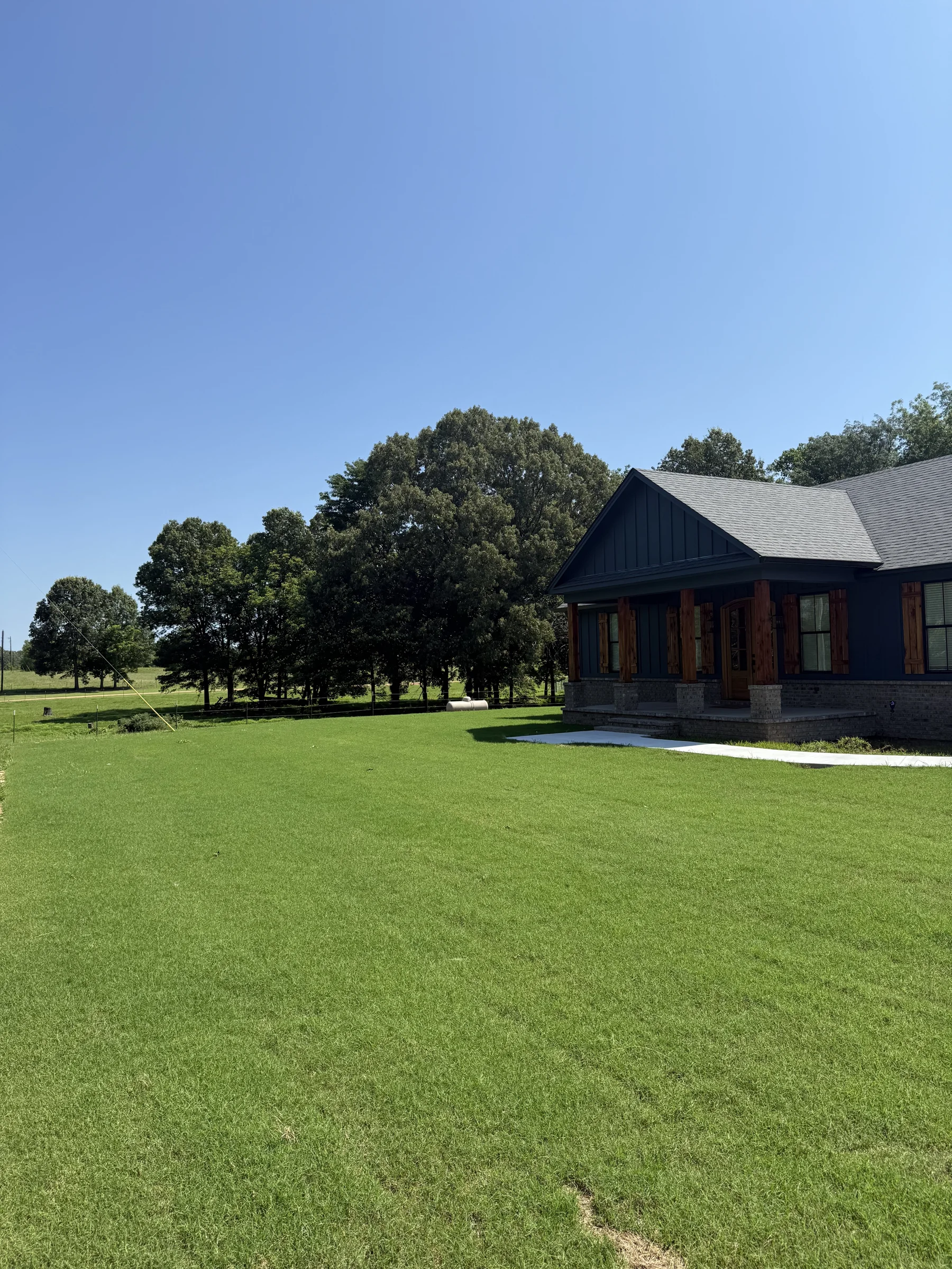 Green lawn beside a dark-sided home, from Ross Sod Farms and Landscaping