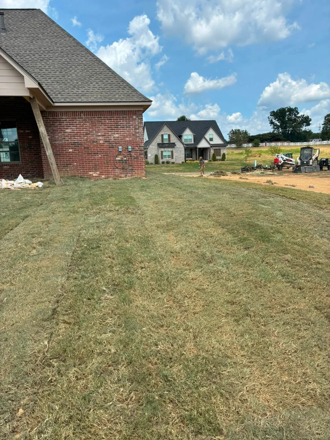 New sod beside a brick garage and driveway