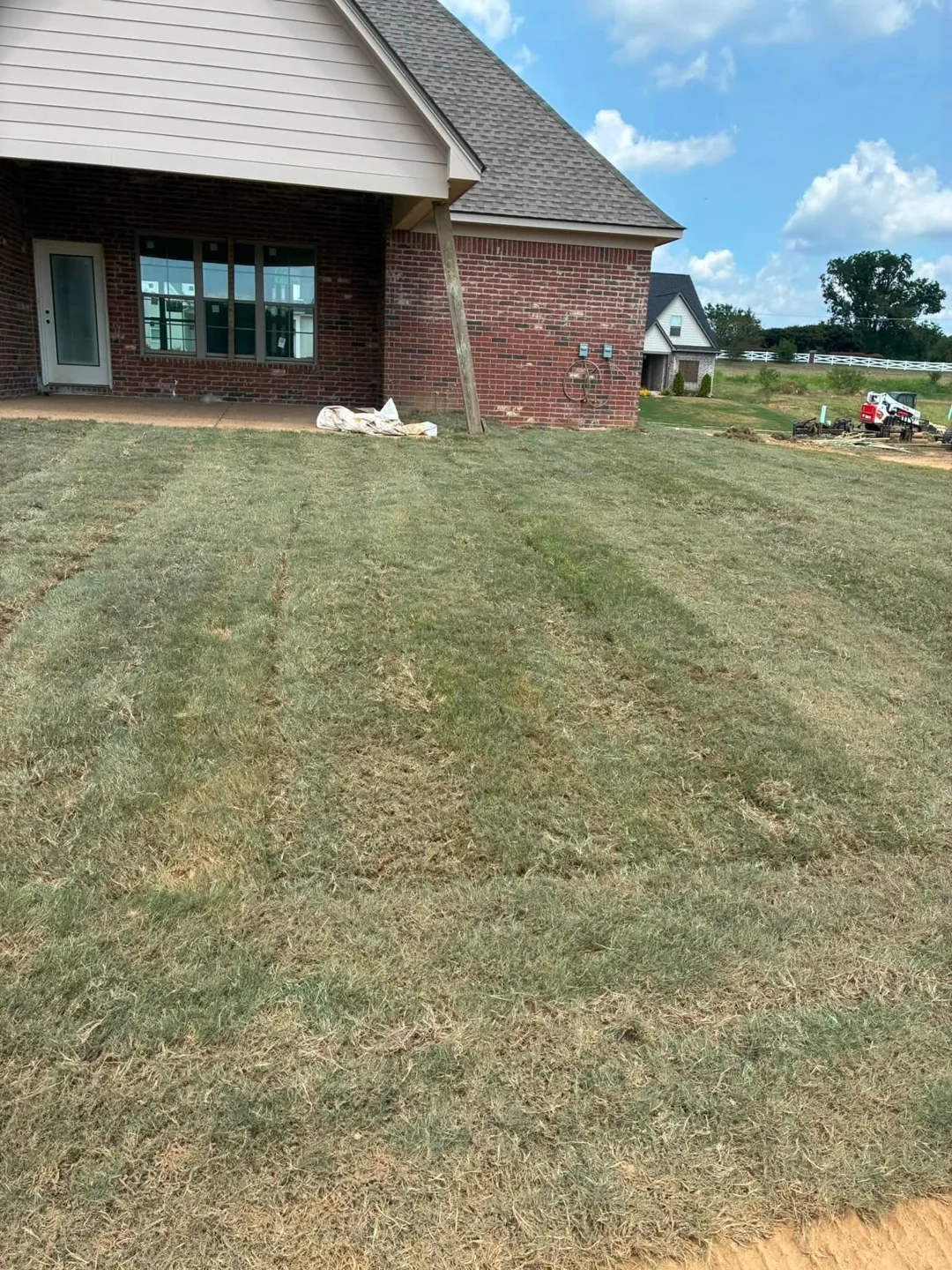 Fresh sod installed beside the windows of a brick home
